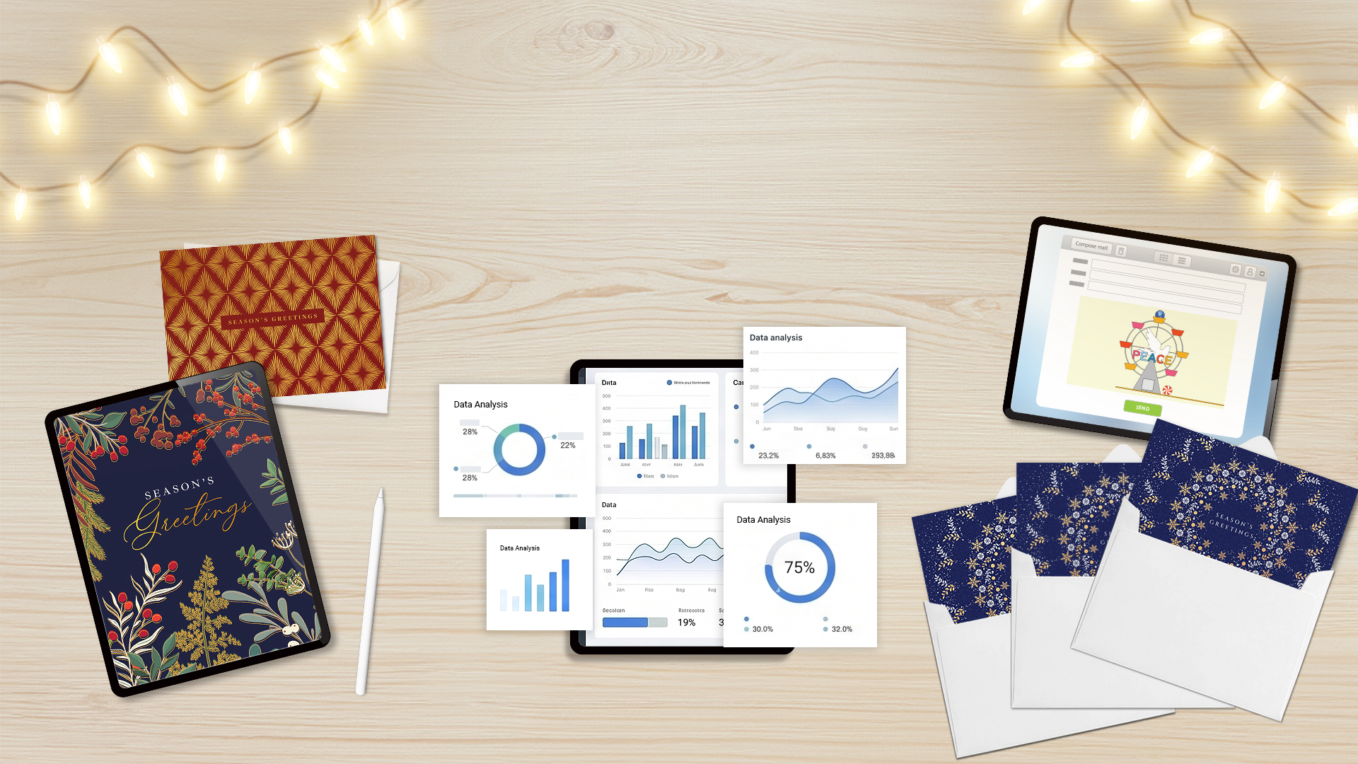 Light wood desk with holiday cards, envelopes, a tablet showing Season's Greetings, charts, and a laptop composing a holiday eCard representing Full Service Solutions